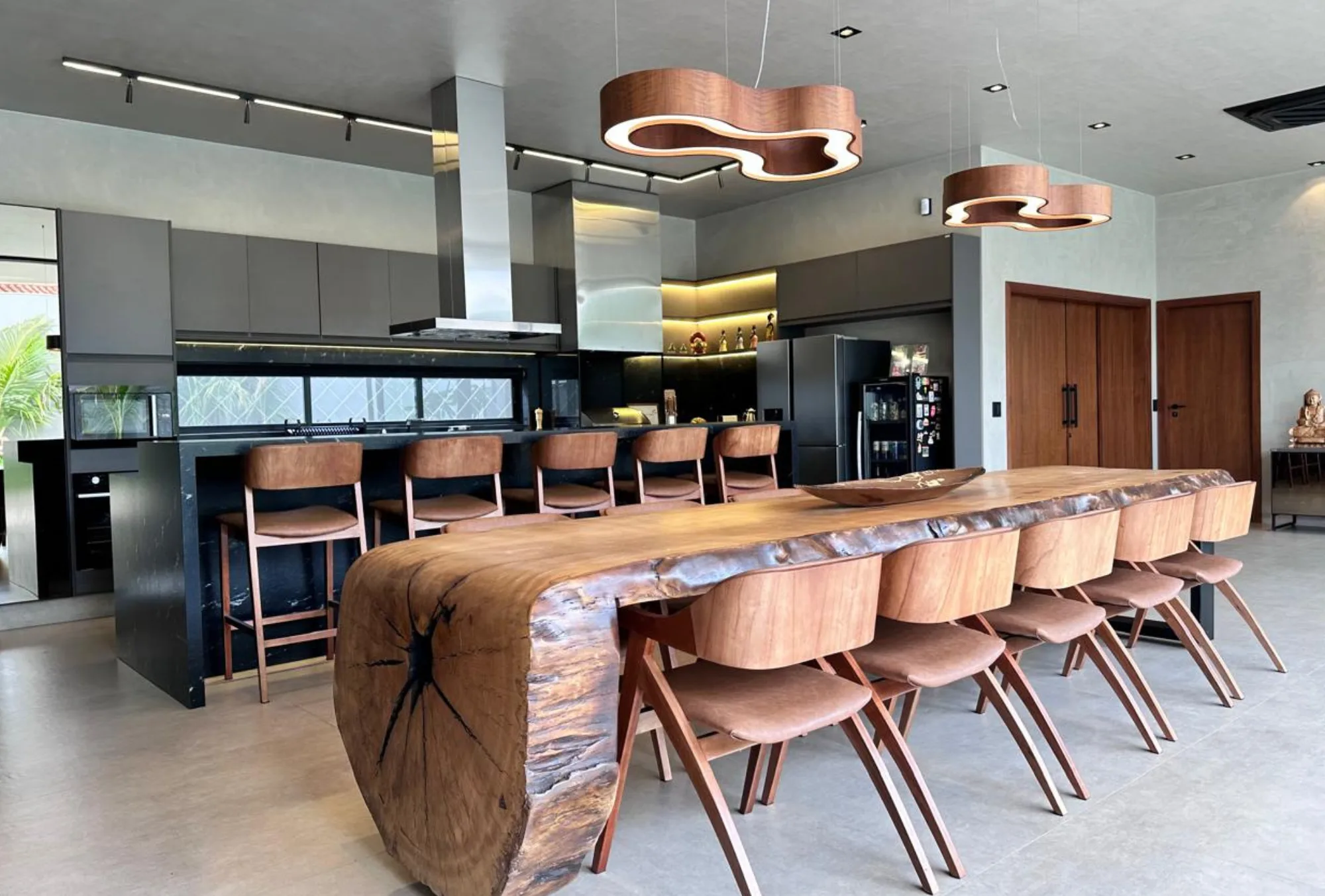 Área gourmet com mesa de madeira maciça e coifa Máxima ao centro